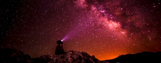 silhouette photo of person holding flashlight under milk way