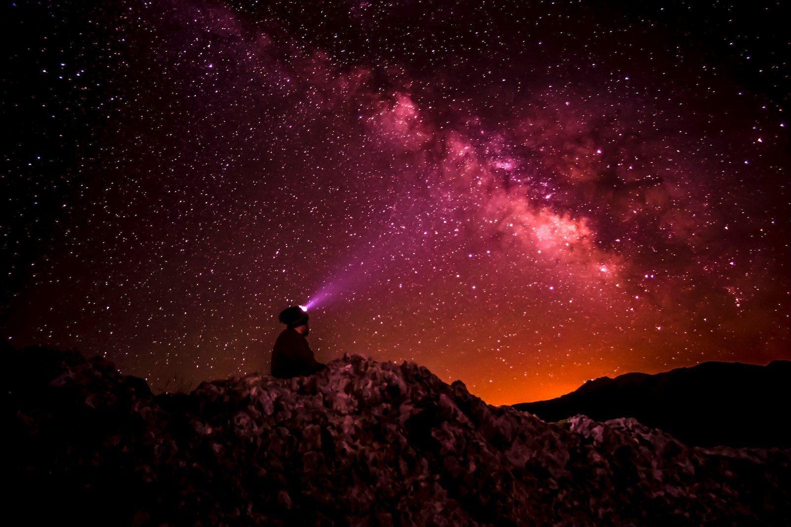 silhouette photo of person holding flashlight under milk way